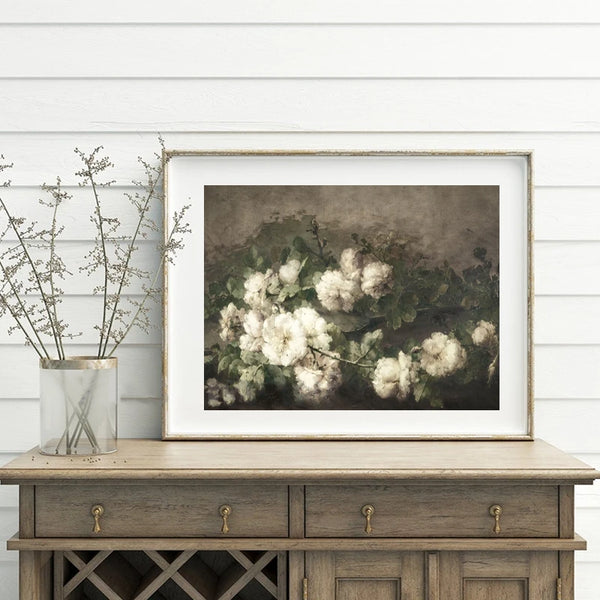 Une toile de style peinture à l'huile vintage représentant un bouquet de fleurs blanches est installé sur une commode en bois. Le style de la déco est classique et rétro. 