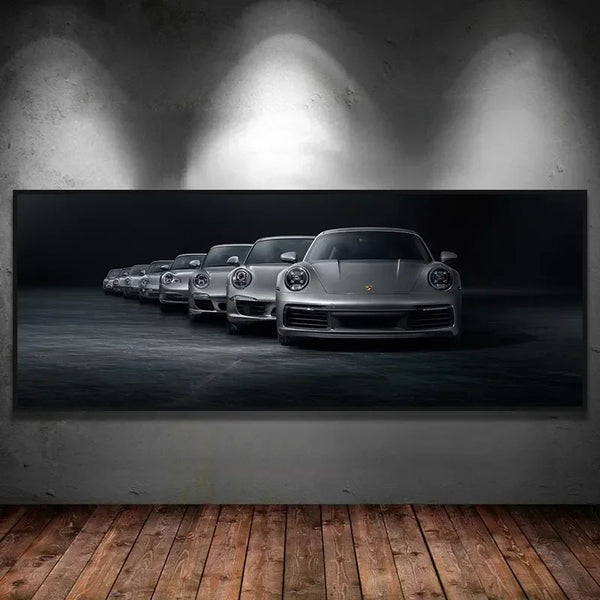 Une toile noir et blanc avec des voitures de sport est installé dans un salon au mur gris et au parquet au sol. 