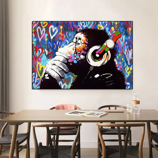 Dans une salle à manger dans un style en bois et scandinave, une toile avec un singe avec un casque audio et des graffitis colorés est affichée. 