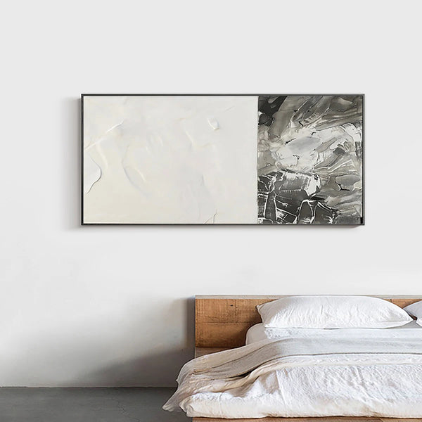 Dans une chambre une toile de style peinture abstraite bicolore blanc et gris est affichée. La chambre est épurée avec un lit en bois et des draps blancs. 