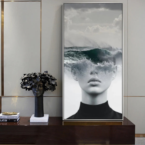 Sur une table basse dans un salon se trouve un tableau d'une femme donc le visage est coupée et remplacée du nez jusqu'au crâne par une photo de la mer. 