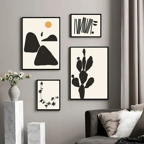 Dans un salon moderne et chic sont affichées quatre toiles de paysage minimaliste et bohème en noir et blanc. 