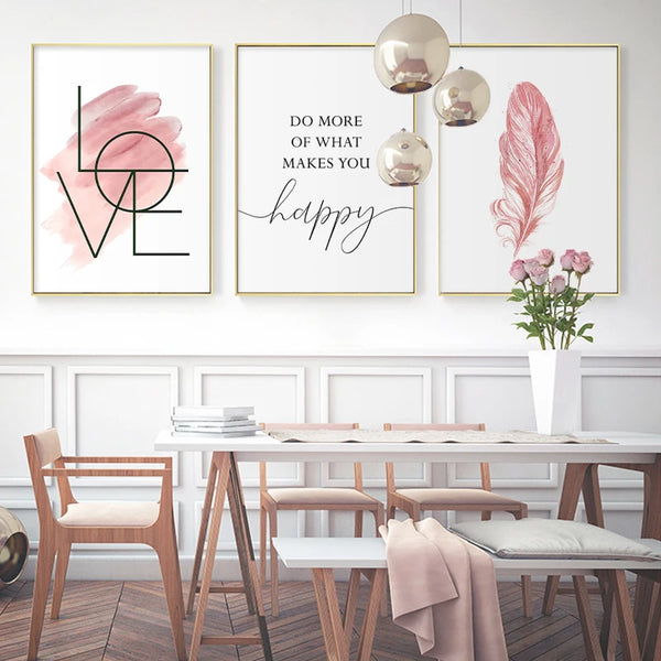 Dans une salle à manger moderne et girly sont affichées trois toiles dans les tons de noir, blanc et rose avec des citations inspirationelles et une plume rose.