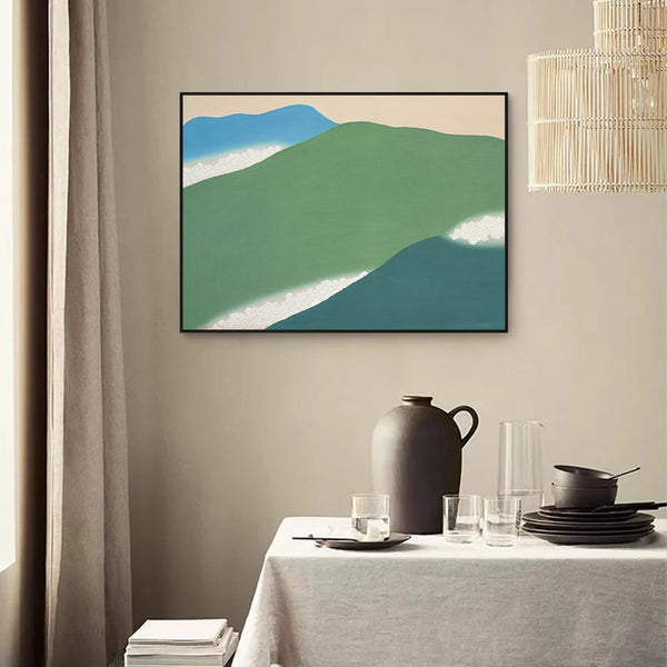 Dans une salle à manger, au style épuré, une toile avec des montagnes minimalistes et des nuages est affichée sur un mur beige. 