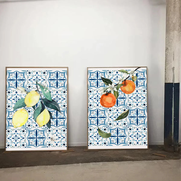 Deux tableaux de nature morte avec fond carrelage blanc et bleu de style mosaïque portugais sont installées dans une pièce. L'une des toiles a des citrons et l'autre à des oranges. 