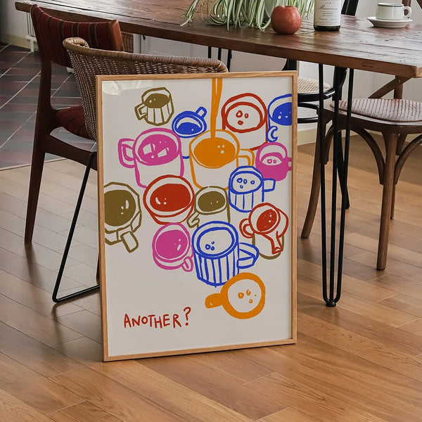 Dans une cuisine au style rétro avec beaucoup de matière bois, une toile pleines de tasses à café colorées et minimalistes avec la mention "Another ?" est posée contre une chaise.