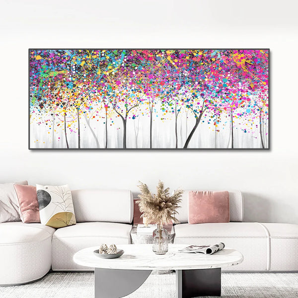 Une toile de style peinture abstraite avec des arbres aux feuillages colorées. Le tableau est affiché dans un salon avec un grand canapé blanc, la déco est moderne et épurée.