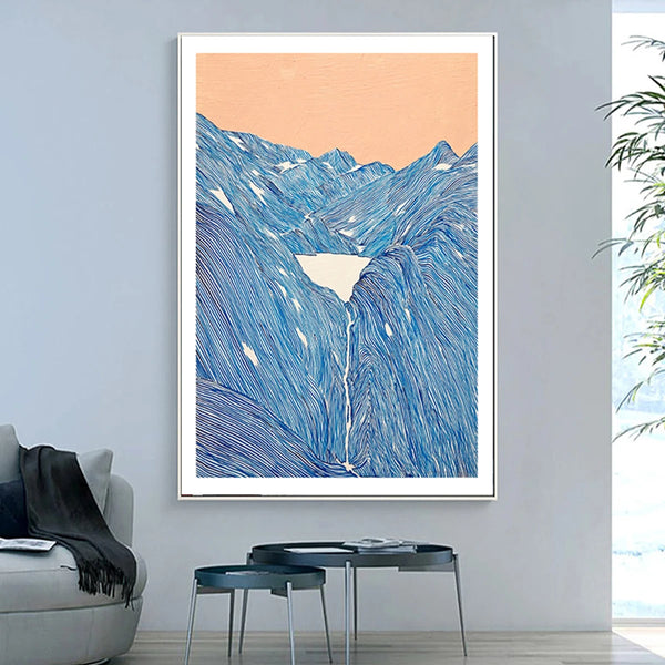Dans un salon au style scandinave et aux couleurs grises se trouve une toile représentant des montagnes faites d'une multitude de traits bleus. Le ciel est orange et il y a un lac au milieu des montagnes. 