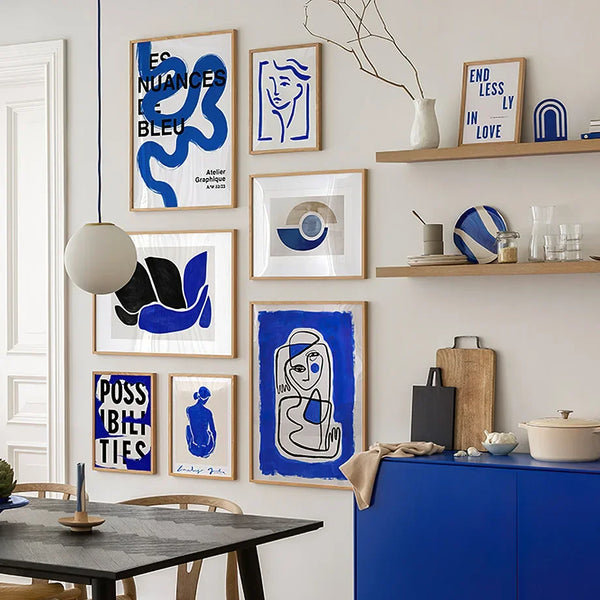 Une cuisine moderne couleur bois et bleu klein est décoré par des toiles de style scandinave représentant des formes géométriques, des femmes dans les tons de bleu. 