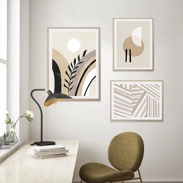 Trois tableaux minimalistes scandinaves sont affichés dans un bureau au style épuré. La déco est scandinave et les affiches sont de couleur blanc, noir et beige. 