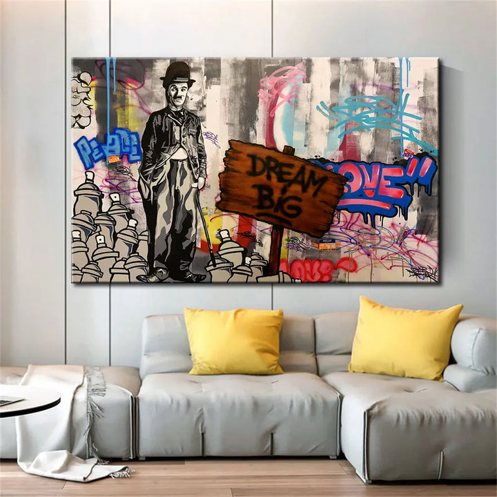 Une toile street art avec Charlie Chaplin et une pancarte Dream big et des graffitis est installée dans un salon au style contemporain.  