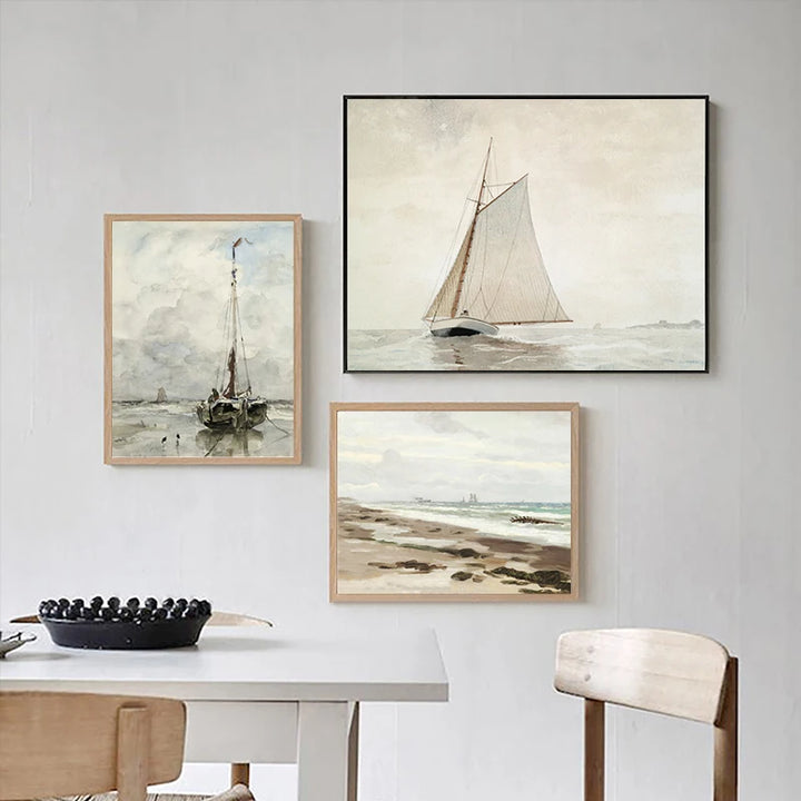 Trois toiles de style peinture à l'huile sur le thème des bateaux et de la mer sont affichées dans une salle à manger. Le style de déco est épuré, classique. 