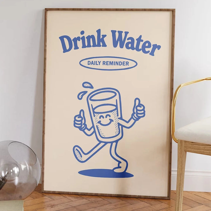 Un tableau est installée dans un salon à côté d'une chaise. Il y a un verre d'eau vintage avec une citation au dessus "Drink water daily reminder"